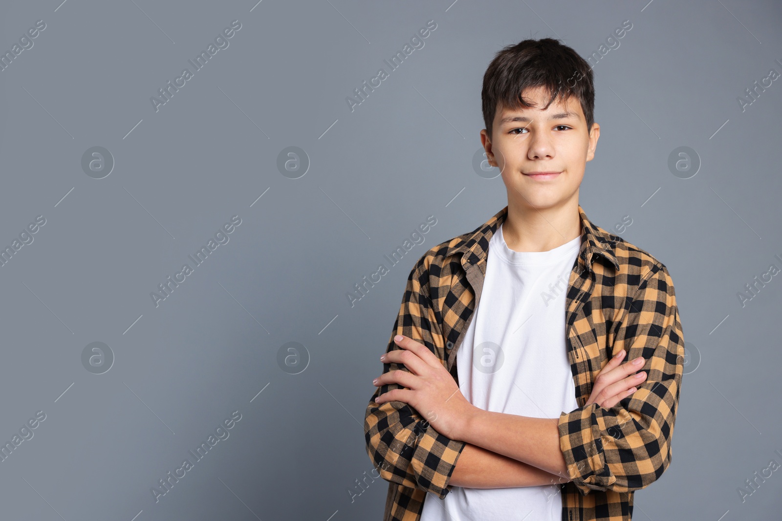 Photo of Portrait of teenage boy with crossed arms on grey background, space for text