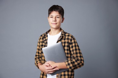 Photo of Portrait of teenage boy with laptop on grey background