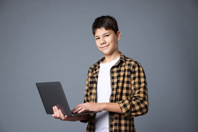 Photo of Portrait of teenage boy with laptop on grey background