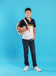 Photo of Full length portrait of teenage boy with backpack on light blue background