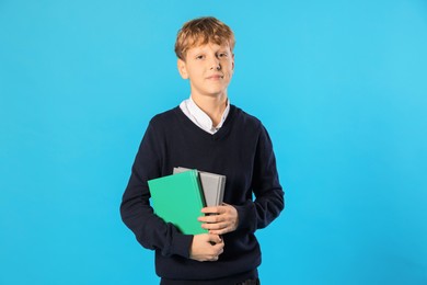 Photo of Portrait of teenage boy with books on light blue background