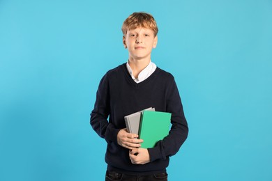 Photo of Portrait of teenage boy with books on light blue background