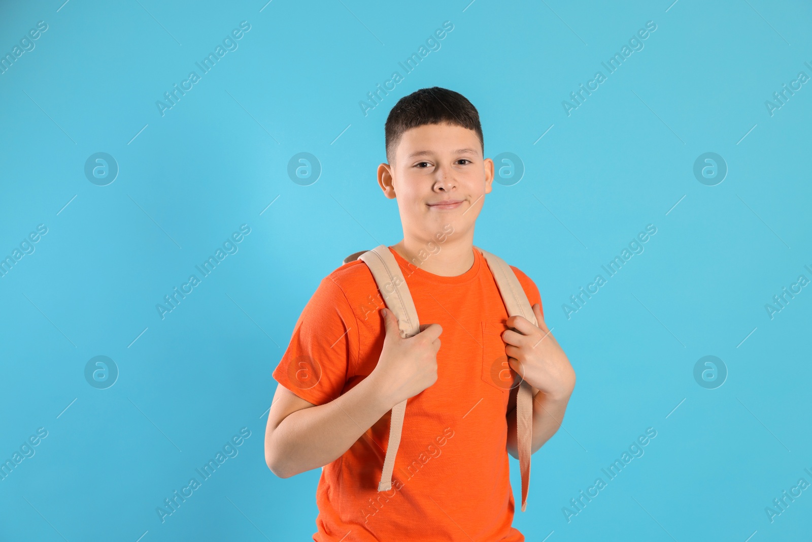 Photo of Portrait of teenage boy with backpack on light blue background