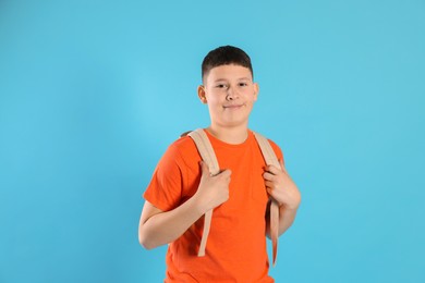 Photo of Portrait of teenage boy with backpack on light blue background