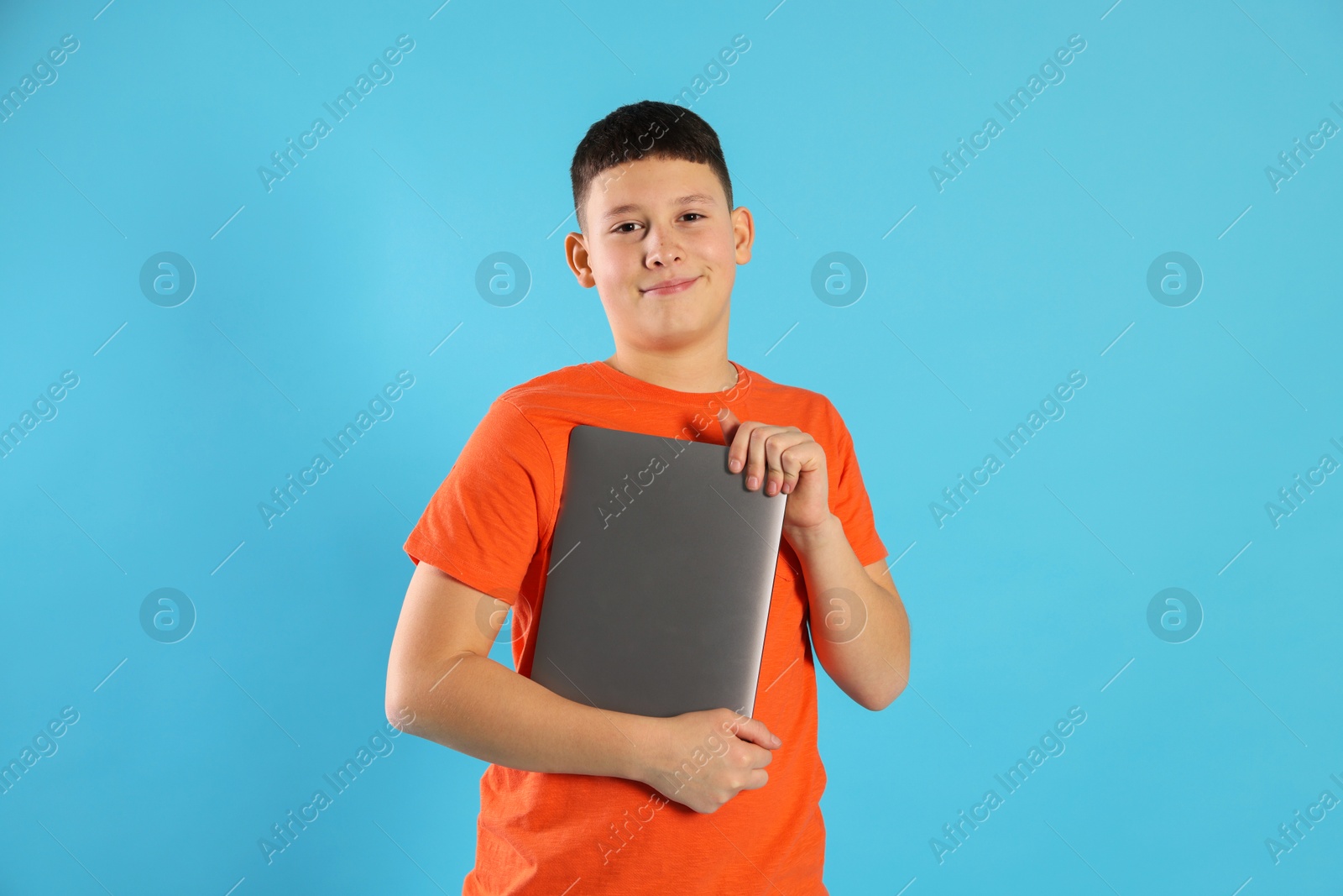 Photo of Portrait of teenage boy with laptop on light blue background