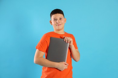 Photo of Portrait of teenage boy with laptop on light blue background