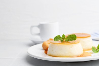 Photo of Tasty puddings with caramel sauce served on white tiled table, closeup. Space for text