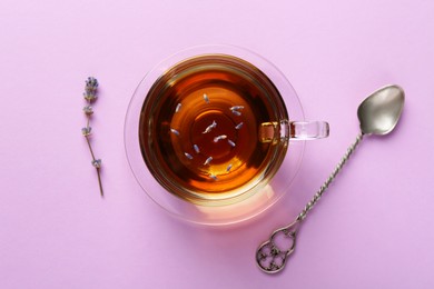 Photo of Aromatic lavender tea in glass cup, spoon and dry flower on pink background, top view