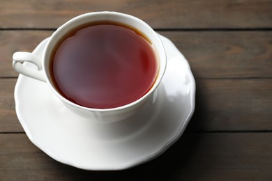 Refreshing black tea in cup on wooden table, closeup