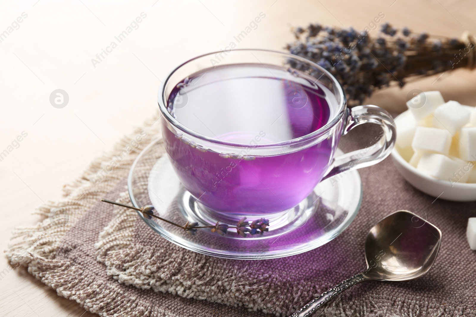 Aromatic lavender tea in glass cup and spoon on wooden table, closeup Photo of Aromatic lavender tea in glass cup and spoon on wooden table, closeup