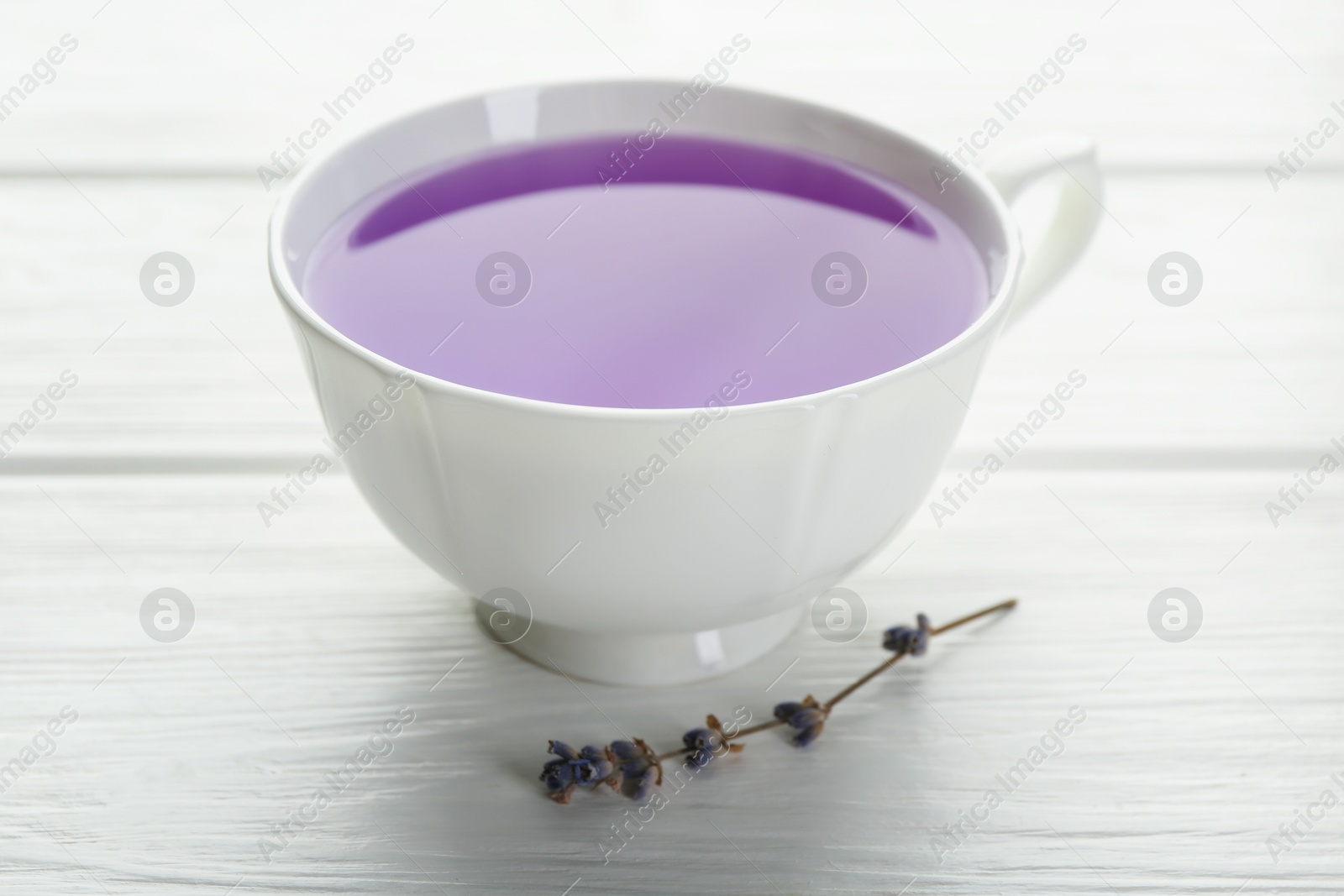 Aromatic lavender tea in cup and dry flowers on white wooden table, closeup Photo of Aromatic lavender tea in cup and dry flowers on white wooden table, closeup