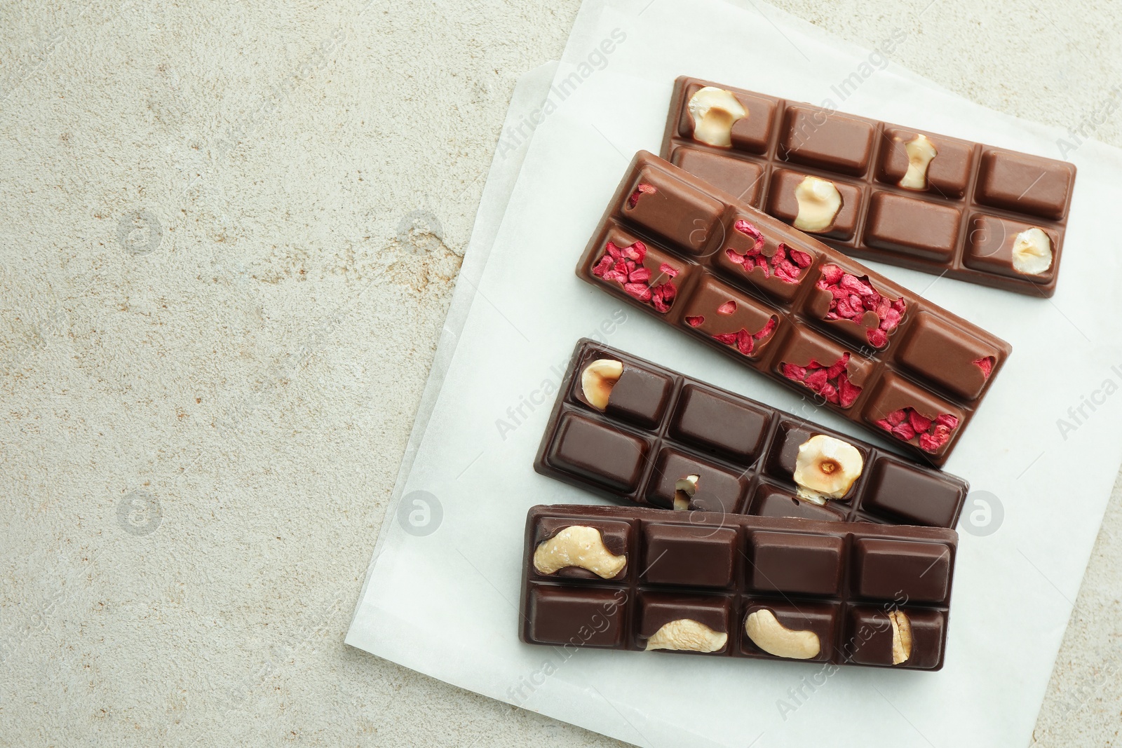 Photo of Delicious chocolate bars with different flavors on light table, flat lay. Space for text