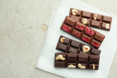 Delicious chocolate bars with different flavors on light table, flat lay. Space for text