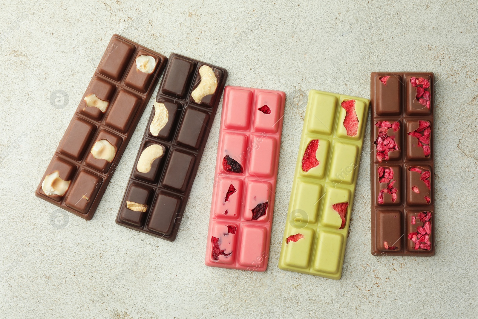 Photo of Delicious chocolate bars with different flavors on light table, flat lay