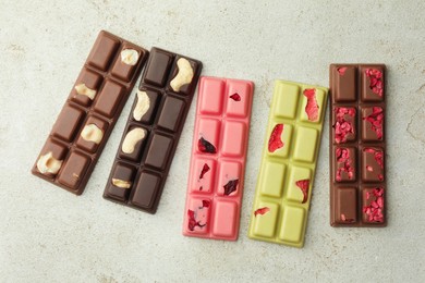 Delicious chocolate bars with different flavors on light table, flat lay