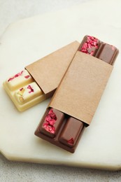 Photo of Delicious chocolate bars with different flavors on light table, closeup