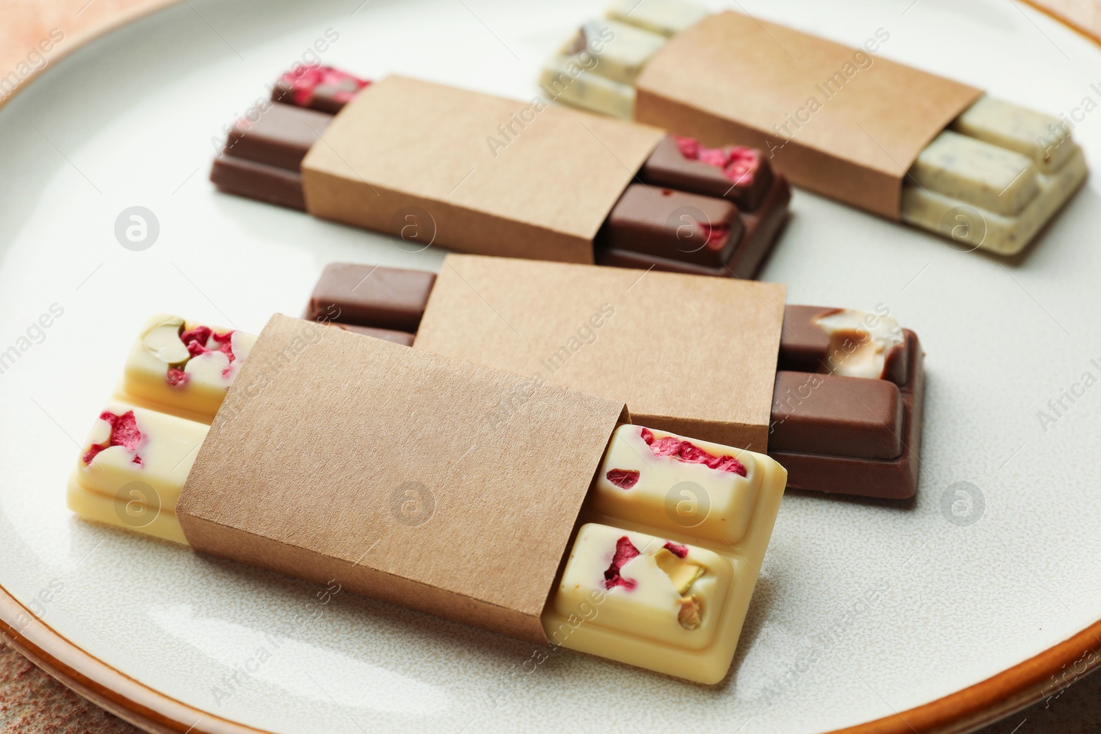 Photo of Delicious chocolate bars with different flavors on light table, closeup