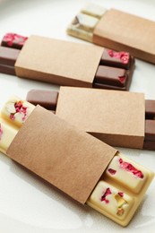 Delicious chocolate bars with different flavors on plate, closeup