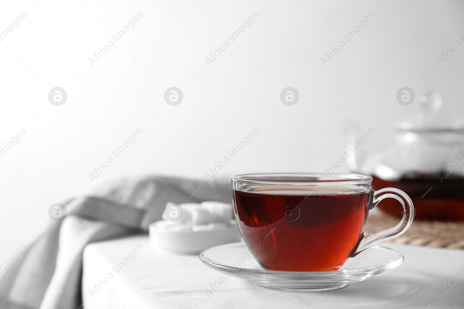 Photo of Refreshing black tea in cup on light table. Space for text