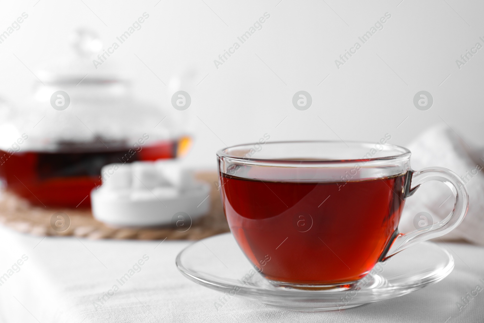 Photo of Refreshing black tea in cup on light table, closeup. Space for text