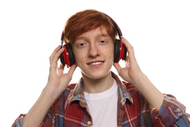 Photo of Smiling teenage boy with freckles listening to music by headphones on white background