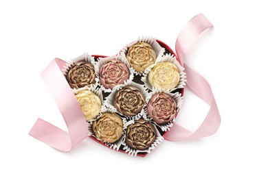 Photo of Flower shaped chocolate bonbons in box and pink ribbon isolated on white, top view