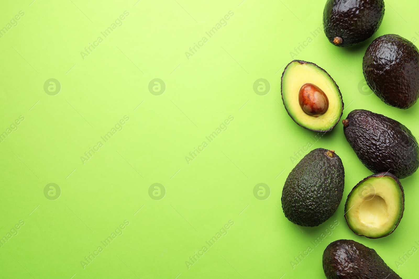 Photo of Fresh ripe avocados on light green background, flat lay. Space for text