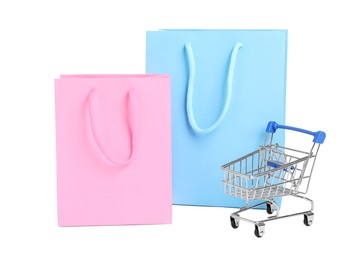 Photo of Shopping bags and mini cart isolated on white