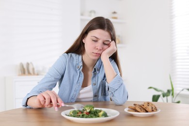 Photo of Sad teen girl holding with salad at home. Eating disorder