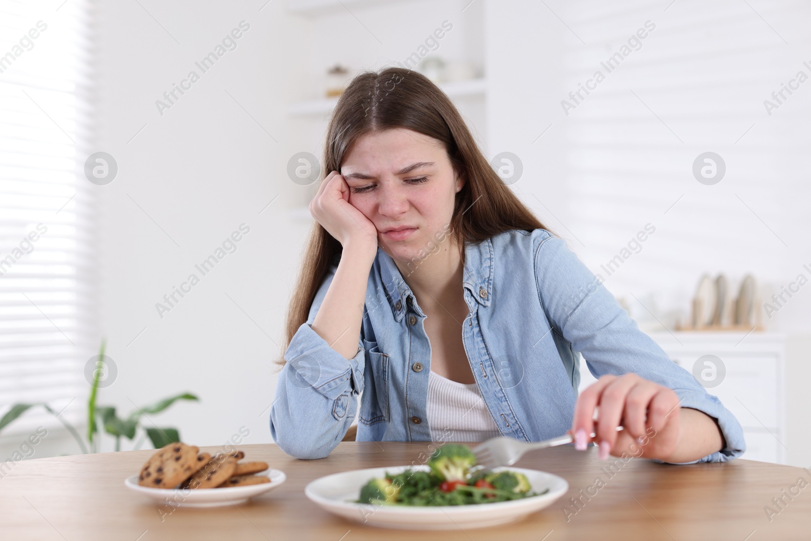 Photo of Sad teen girl holding with salad at home. Eating disorder