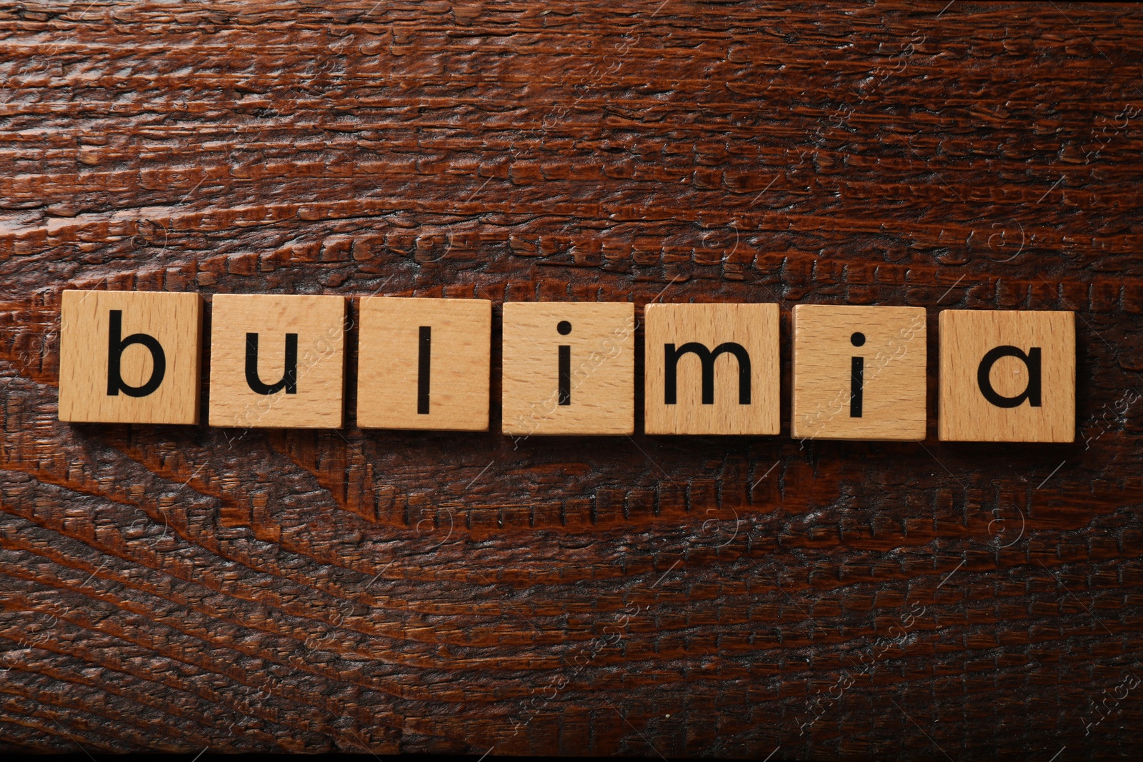 Photo of Squares with word Bulimia on wooden table, flat lay