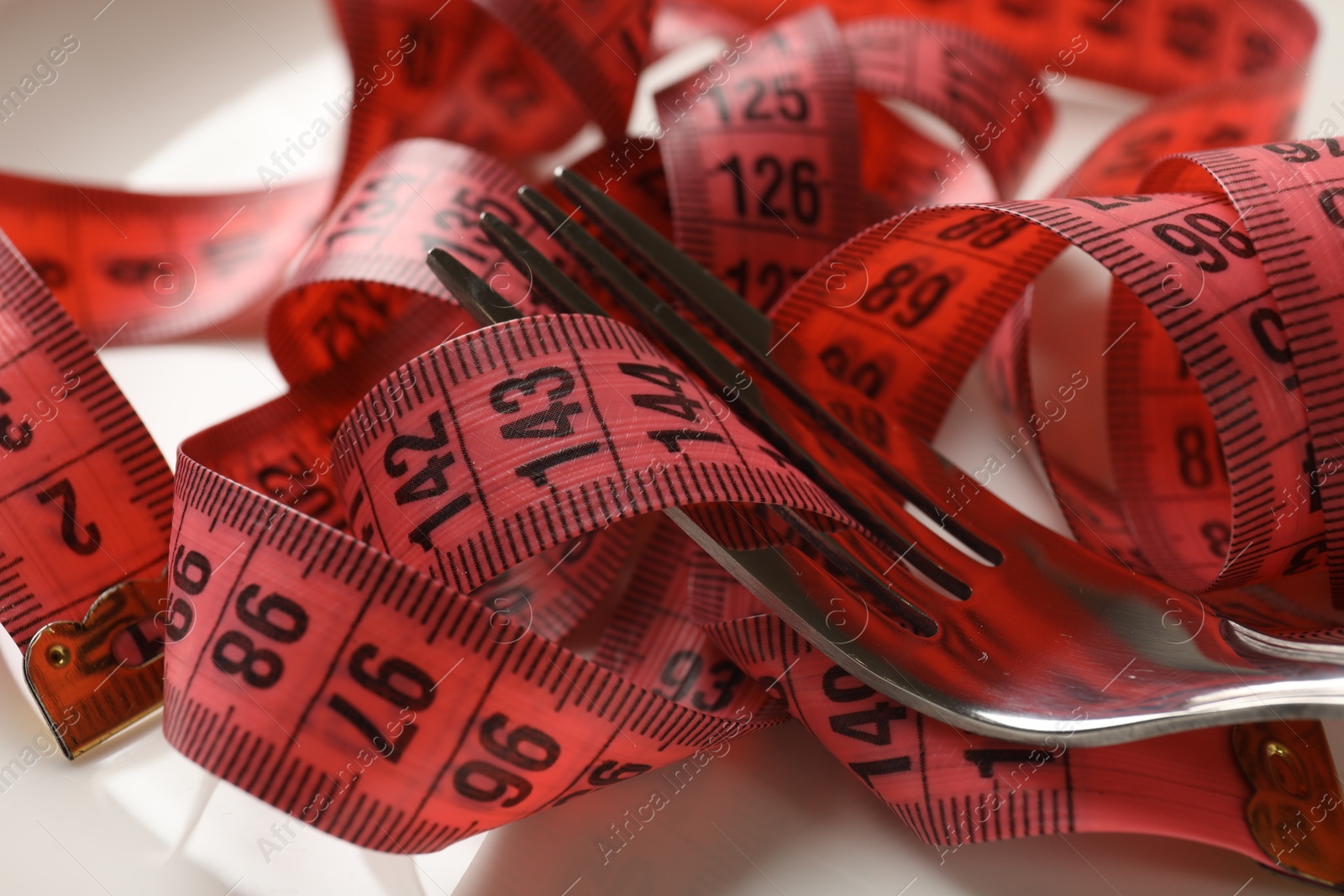 Photo of Bulimia. Fork and measuring tape on plate, closeup