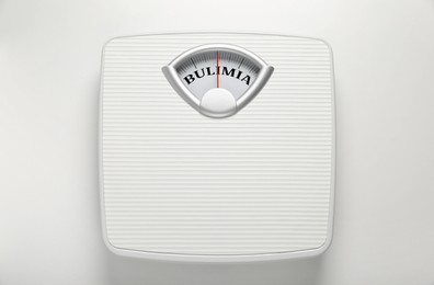 Image of Mechanical scales with word Bulimia instead of numbers on white background, top view