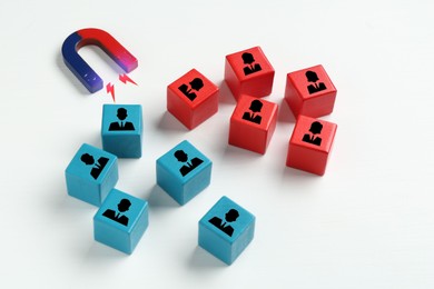 Image of Magnet attracting wooden cubes with human figures on white background. Recruitment or customer acquisition