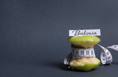 Image of Apple core with measuring tape and word Bulimia on dark grey background, space for text