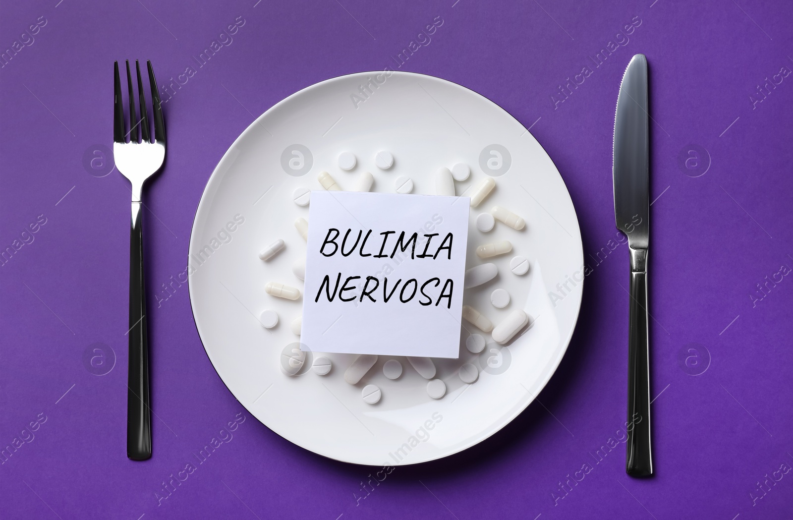 Image of Cutlery near plate with pills and word Bulimia Nervosa on dark violet background, flat lay