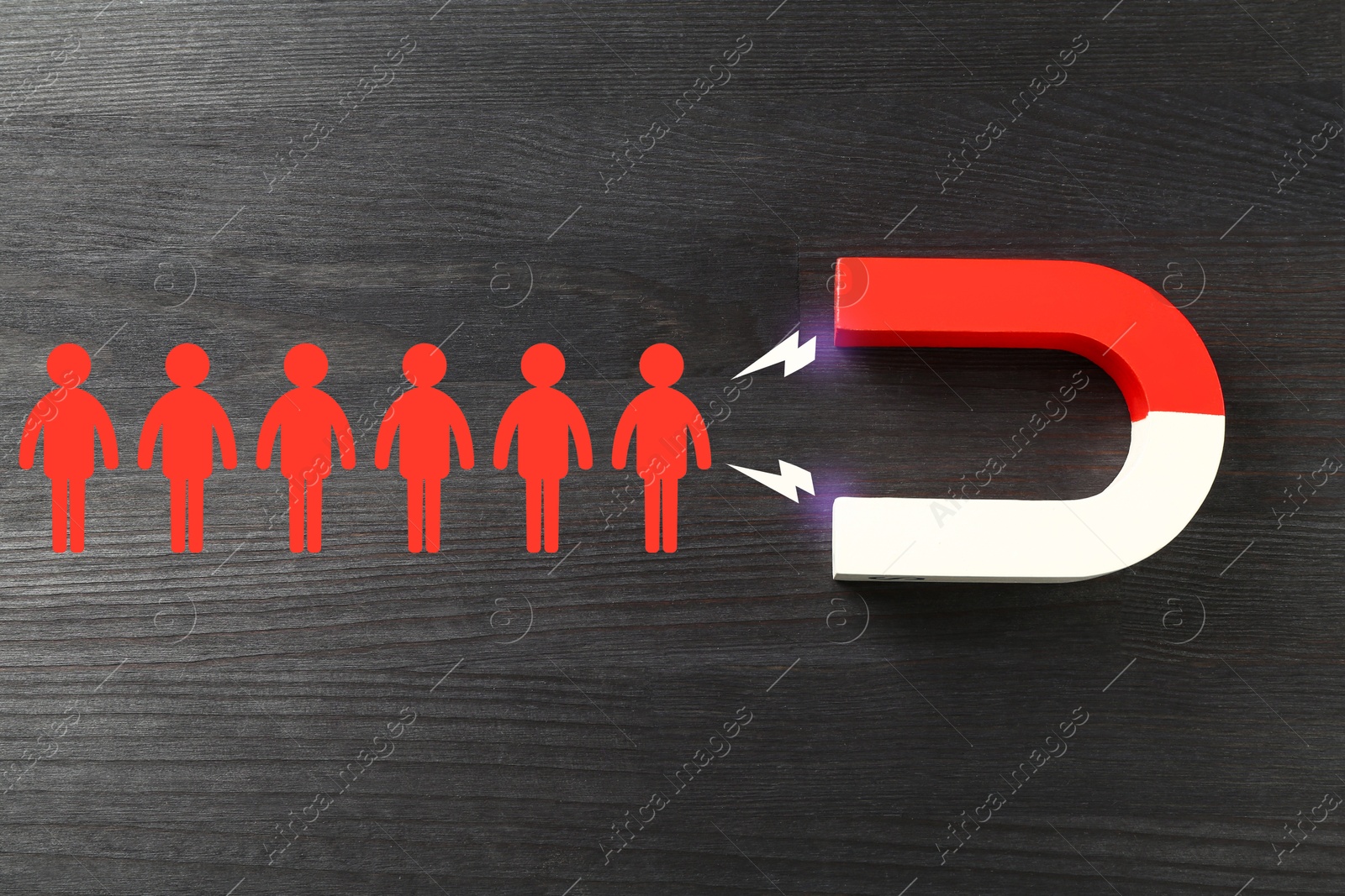 Image of Magnet attracting red human figures on wooden background, top view. Recruitment or customer acquisition