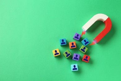 Image of Magnet attracting colorful cubes with human figures on green background, top view. Recruitment or customer acquisition