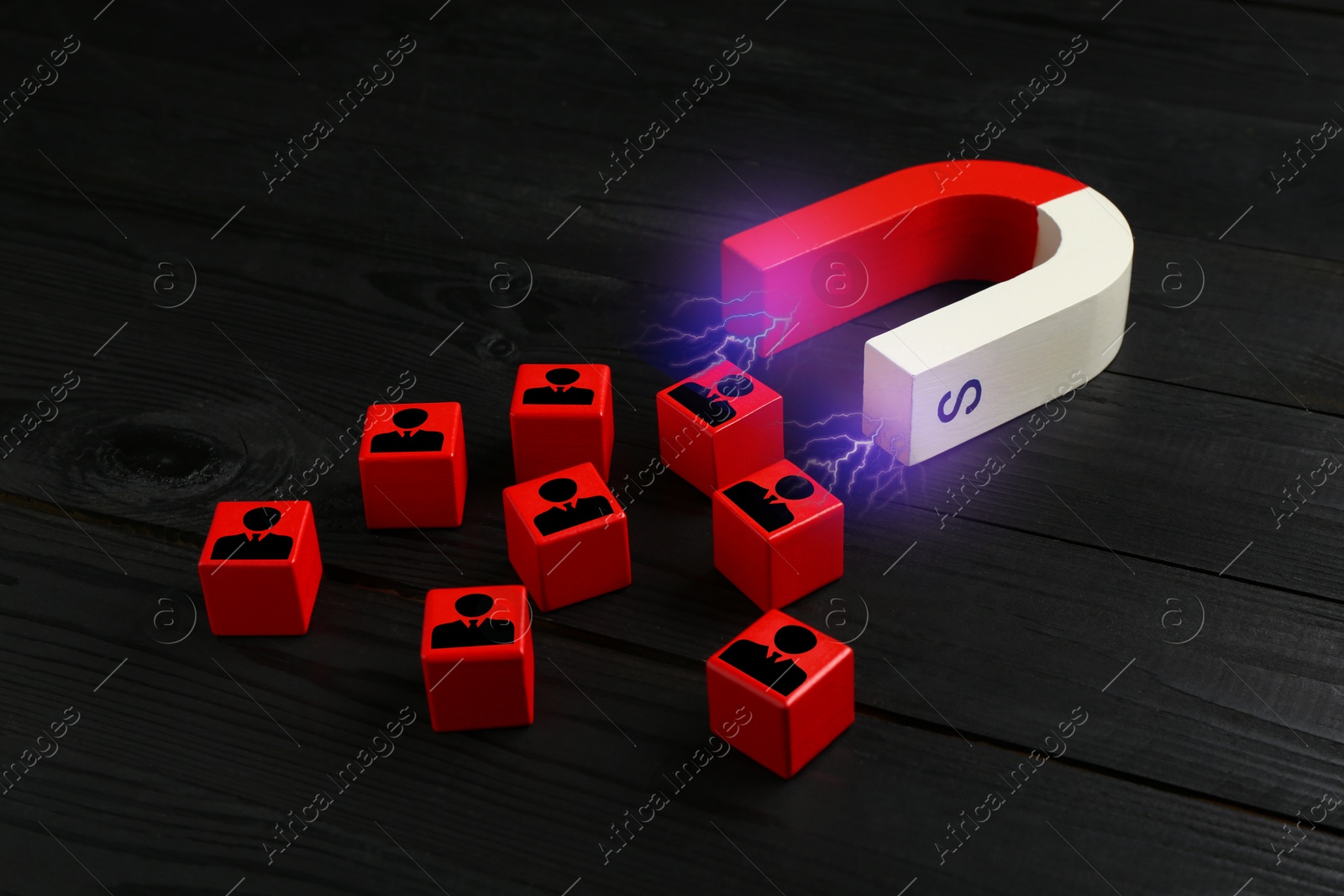 Image of Magnet attracting red cubes with human figures on back wooden background. Recruitment or customer acquisition