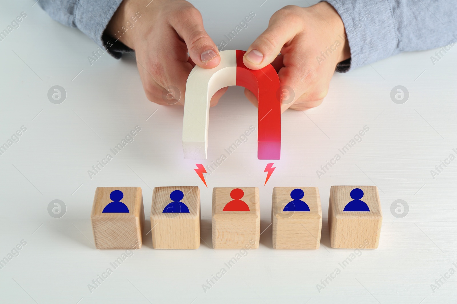 Image of Man attracting wooden cubes with magnet on white background, closeup. Recruitment or customer acquisition