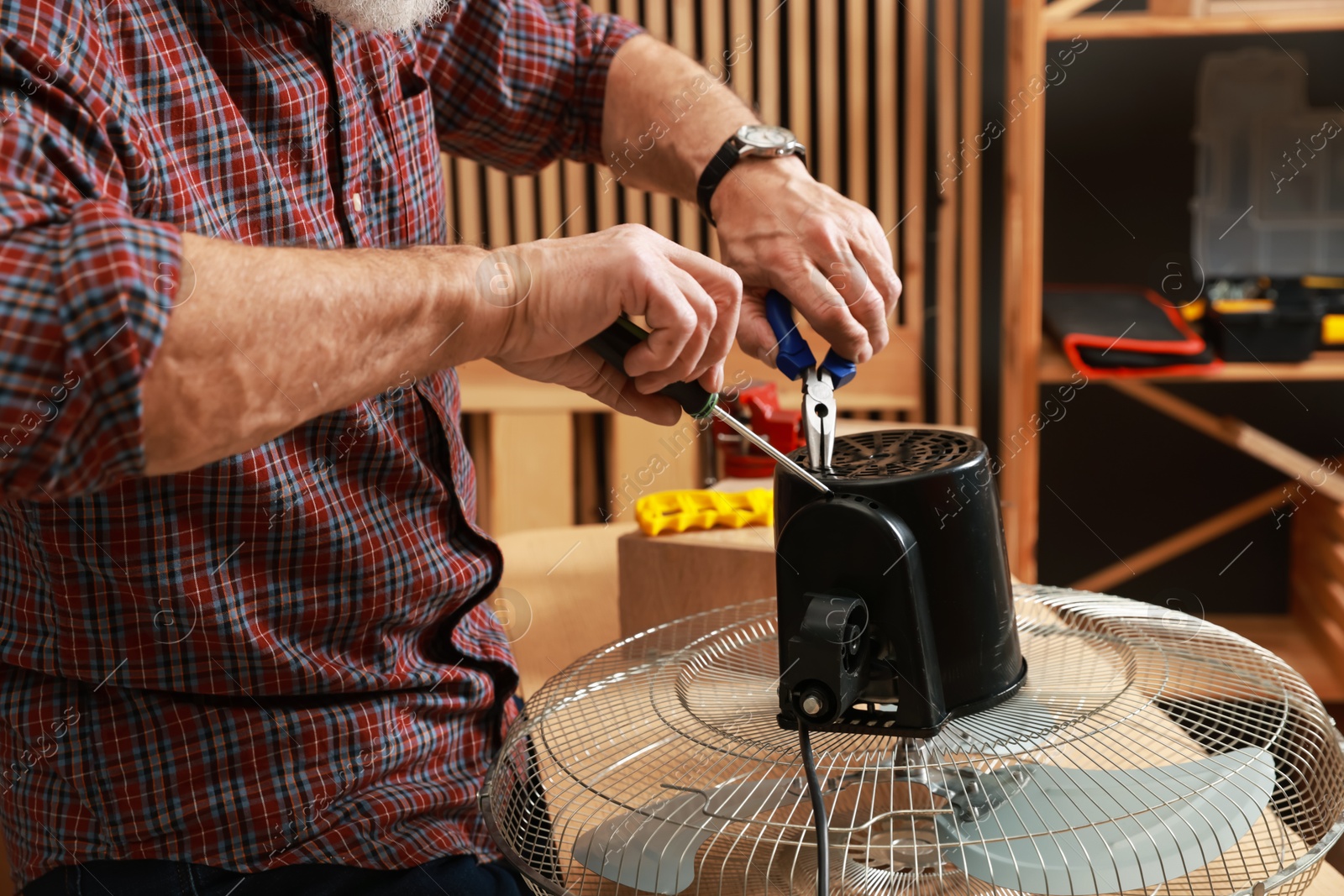 Photo of Relaxing hobby. Senior man repairing fan in workshop, closeup