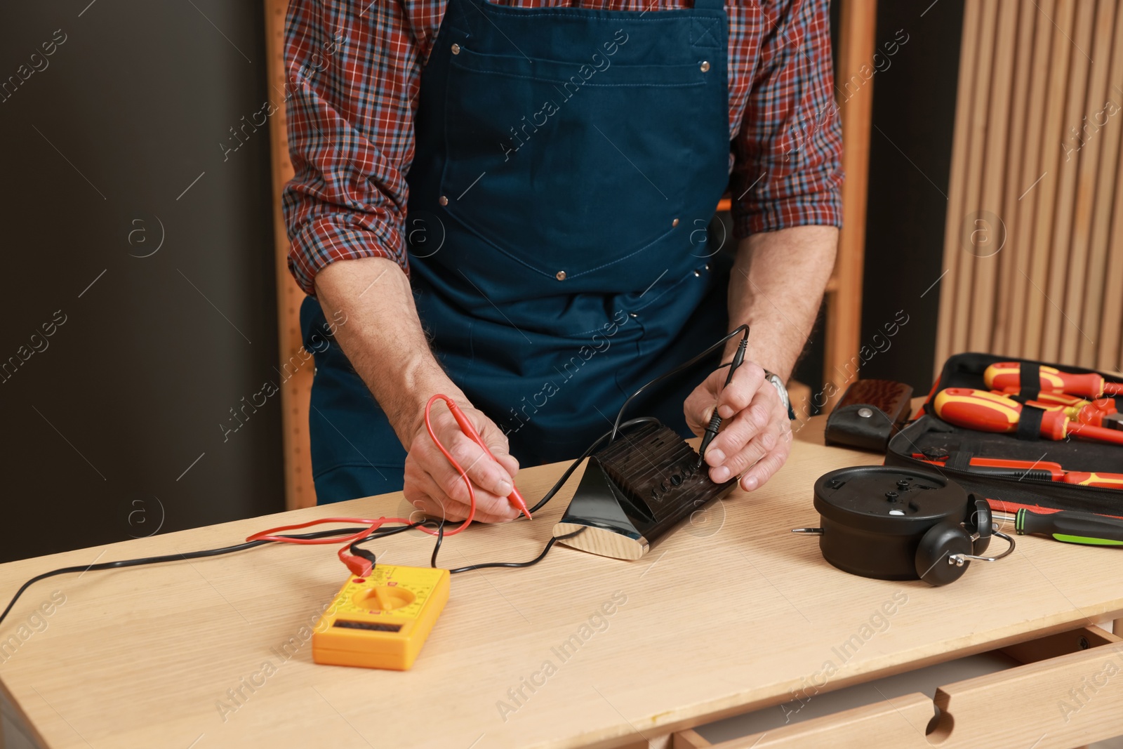 Photo of Relaxing hobby. Senior man testing alarm clock with multimeter in workshop, closeup