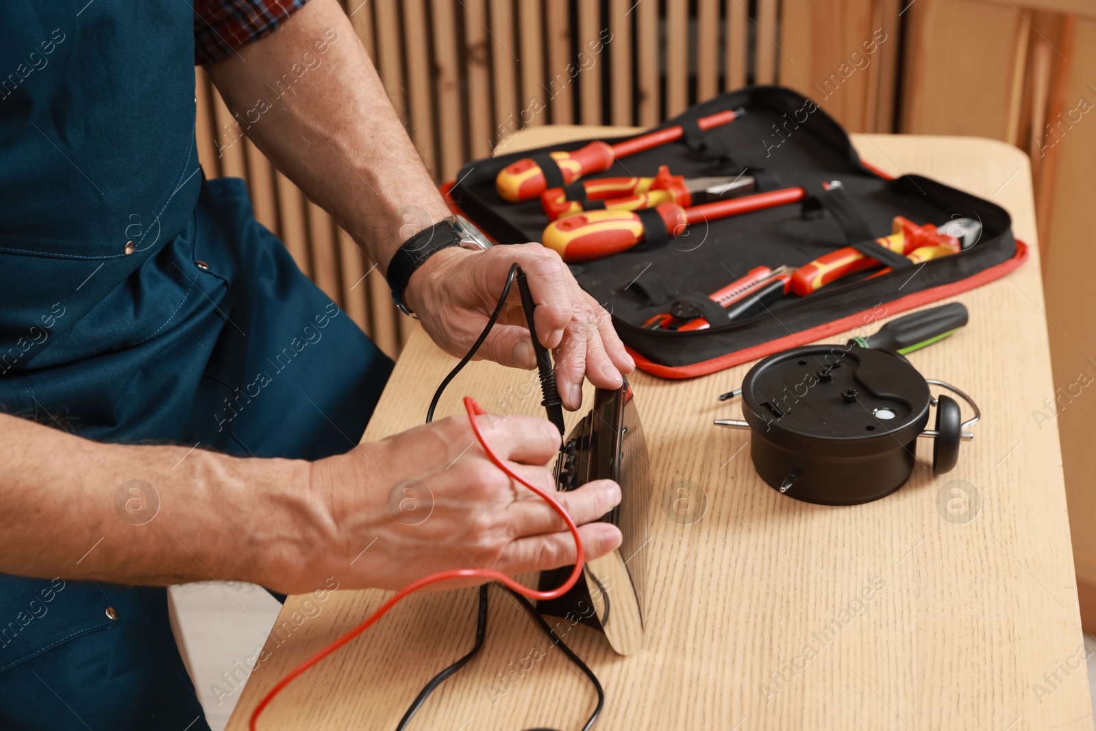 Photo of Relaxing hobby. Senior man testing alarm clock with multimeter in workshop, closeup