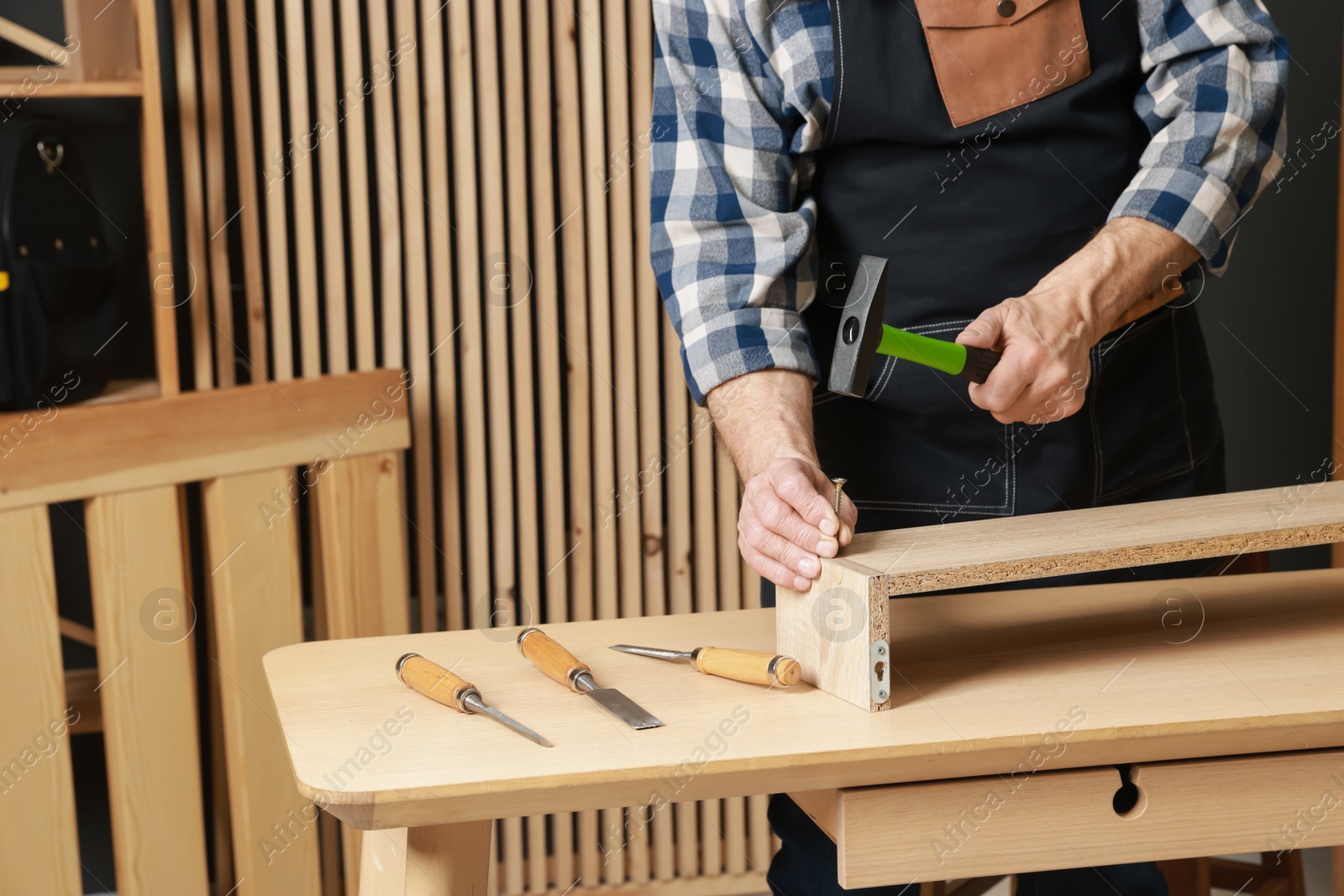 Photo of Relaxing hobby. Senior man repairing wooden shelf with hammer and nail in workshop, closeup