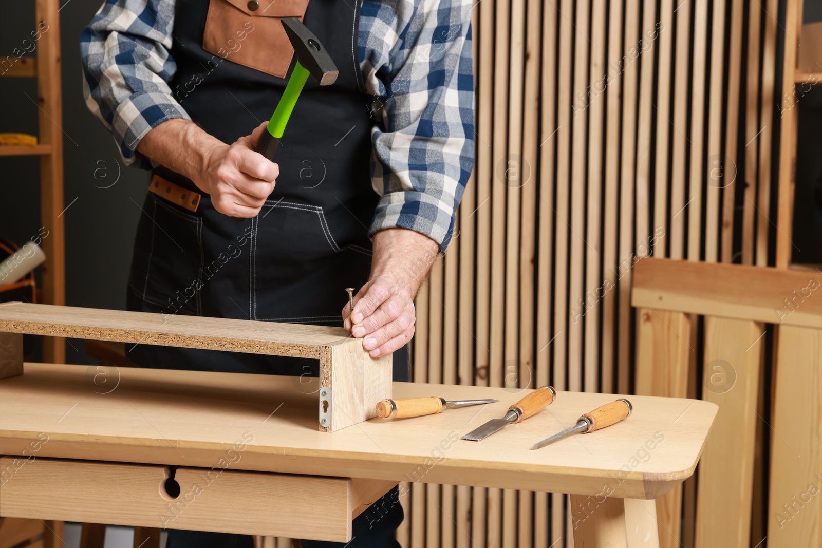 Photo of Relaxing hobby. Senior man repairing wooden shelf with hammer and nail in workshop, closeup