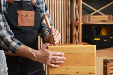 Photo of Relaxing hobby. Senior man repairing wooden stool with chisel in workshop, closeup