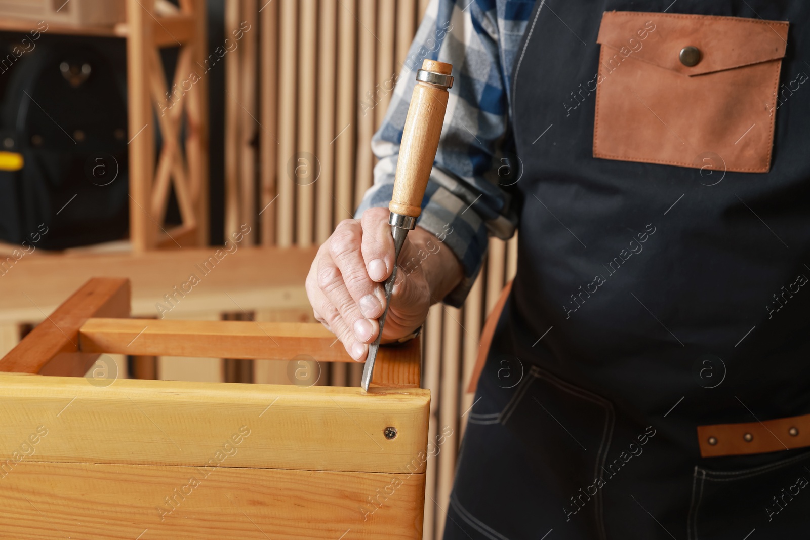 Photo of Relaxing hobby. Senior man repairing wooden stool with chisel in workshop, closeup