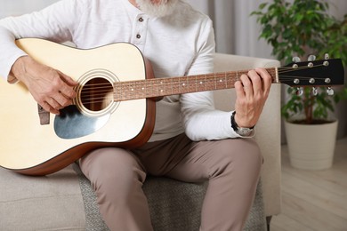 Photo of Relaxing hobby. Senior man playing guitar on sofa at home, closeup