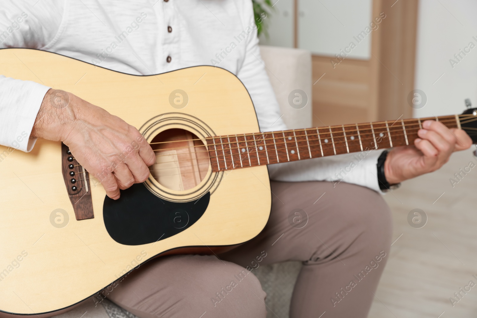 Photo of Relaxing hobby. Senior man playing guitar at home, closeup