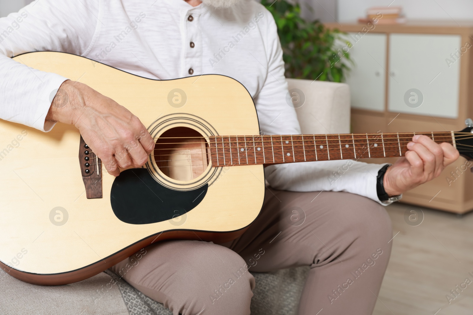 Photo of Relaxing hobby. Senior man playing guitar on sofa at home, closeup